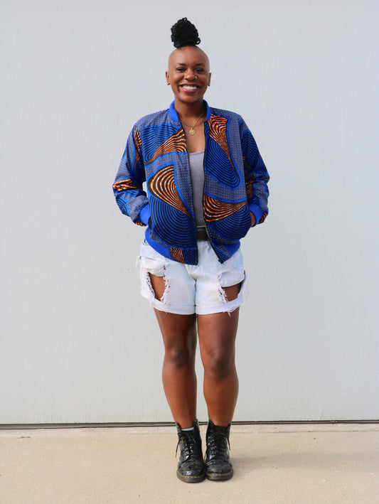 "Kelechi" is a Nigerian Igbo word for "Thank God"  Bomber jacket with a round neck and long sleeves, blue ribbed trimmings, side pockets, and front zip closure.  100% Cotton.