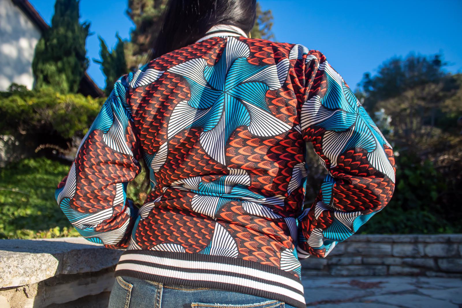 "Kene" is a Nigerian Igbo word meaning "thank"; used to express gratitude or appreciation.   Bomber jacket with black/white ribbed trim neck, cuffs and bottom; side pockets and zip closure.  100% Cotton